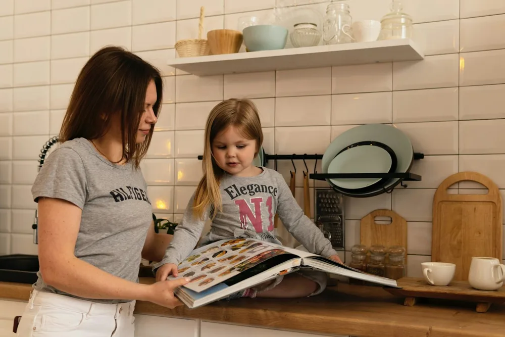 Mãe e filha a ler um livro de receitas na cozinha